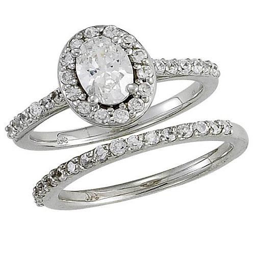 Halo style engagement ring with oval shape center diamond and round cut side diamonds, paired with matching wedding band