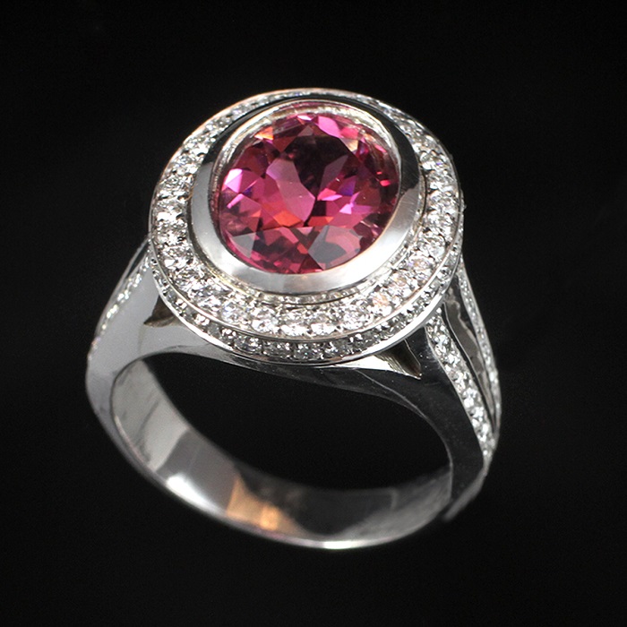 Halo style ring with oval pink tourmaline and round cut diamonds