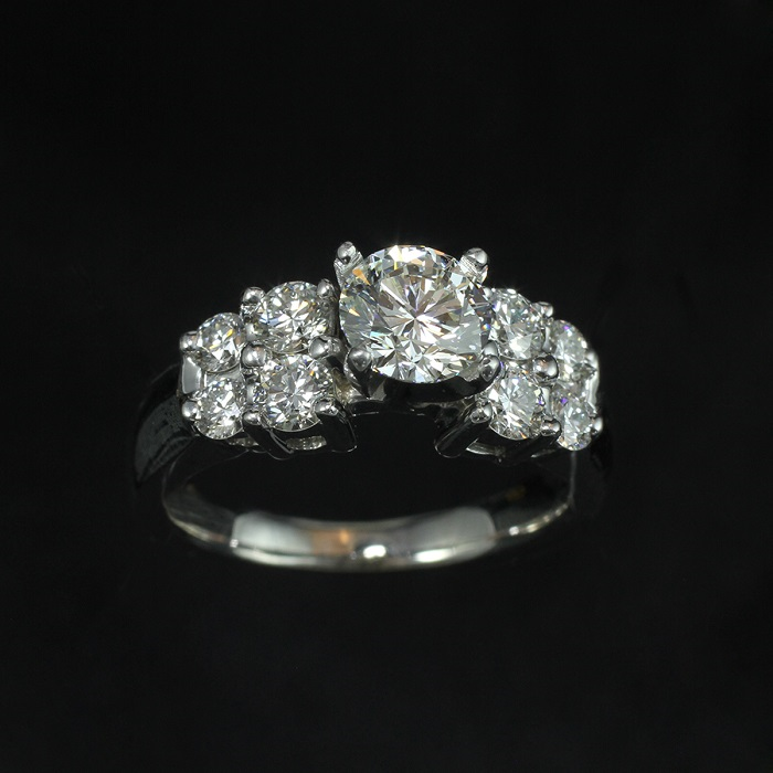 Step style engagement ring with round cut center and side diamonds